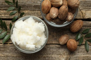 Doğal Shea tereyağı, fındık ve yapraklar ahşap masada, düz yatıyordu.
