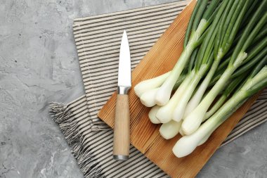 Taze taze yeşil soğanlar, kesme tahtası ve bıçakla gri desenli masa, düz yatış. Metin için boşluk