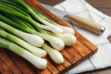 Taze taze soğanlar, ahşap masada kesme tahtası ve bıçakla yakın plan.
