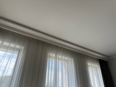 Güzel perdeler pencerenin yanında asılı, alçak açılı manzara.