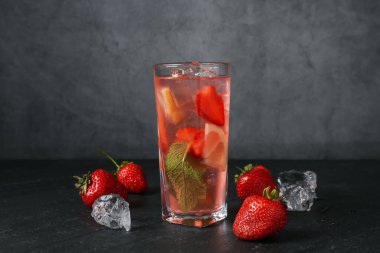 Çilekli içecek ve koyu dokulu masa üzerindeki buz gri arka planda, yakın plan.