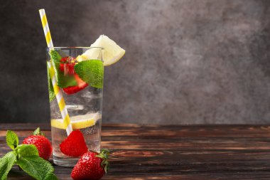 Çilekli, limonlu ve naneli içecek, ahşap masada, gri desenli arka planda. Metin için boşluk
