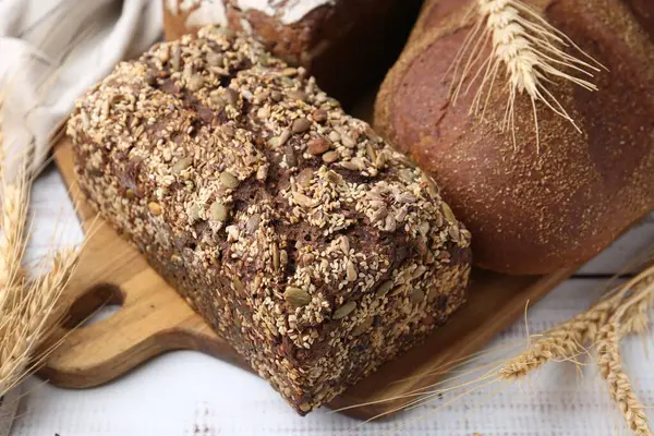 Taze ekmek somunları ve çiviler beyaz ahşap masada, yakın plan.