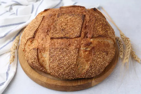 Taze pişmiş ekmek, susam tohumları ve açık gri masada çiviler, yakın plan.