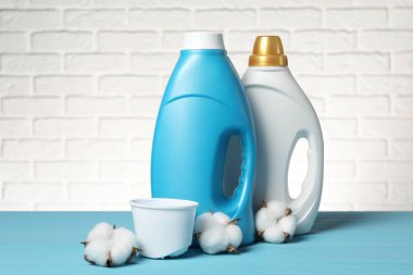 Beyaz tuğla duvara karşı açık mavi masada yumuşatıcı ve pamuk çiçekleri.