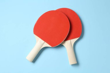 Açık mavi zemin üzerinde pinpon raketleri, düz yatıyordu