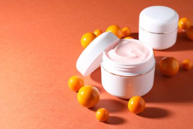 Kavanozlar dolusu nemlendirici vücut kremi ve turuncu arka planda toplar, yakın plan. Metin için boşluk