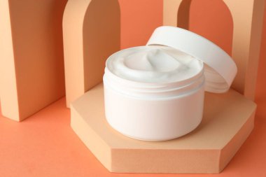 Turuncu arka plandaki kavanozda nemlendirici vücut kremi sunumu, yakın plan.