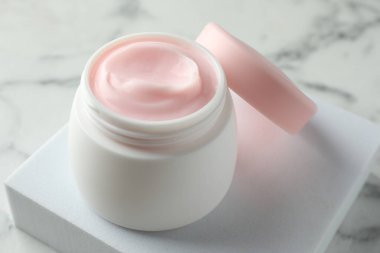 Beyaz mermer masanın üzerinde bir kavanoz nemlendirici vücut kremi, yakın plan.