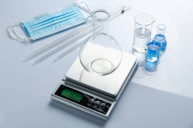 Beyaz arka planda matara ve diğer laboratuvar ekipmanları ile ölçeklendir