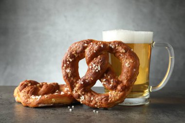 Lezzetli krakerler ve koyu dokulu masada bir bardak bira. Gri arka planda, yakın planda.