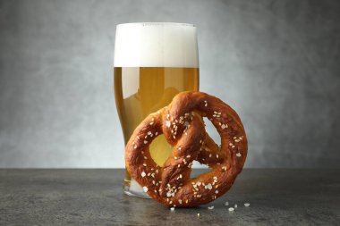 Lezzetli kraker ve bir bardak bira koyu desenli masada gri arka planda, yakın plan