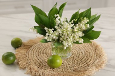 Güzel bir zambak buketi ve beyaz mermer masa üzerinde misket limonu, yakın plan.