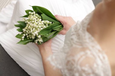 Gelin, vadideki güzel zambaklardan bir buket, kapalı bir kanepede, yakın plan.