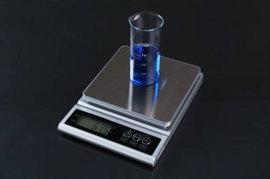 Siyah ayna masasında numune şişesiyle ölçeklendir, yakın plan.