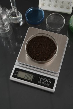 Siyah ayna masasının üzerinde Petri kabı ve diğer laboratuvar camlarıyla ölçeklendir.