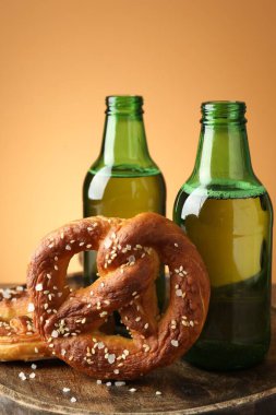 Lezzetli krakerler ve bira şişeleri ahşap tahta üzerinde, bej renk gradyan arka planda, yakın plan