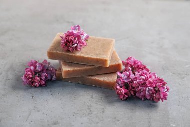 Gri desenli masada sabun ve leylak çiçekleri yığını, yakın plan.