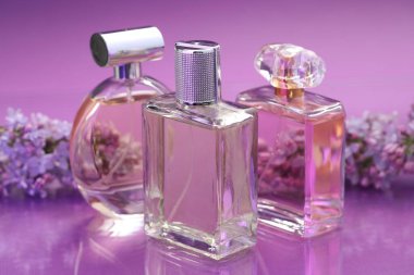 Parfümlü şişeler ve ayna yüzeyinde leylak çiçekleri renk değişimine karşı, yakın plan