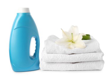 Bir şişe yumuşatıcı, istiflenmiş havlular ve beyaz üzerine izole edilmiş çiçek.