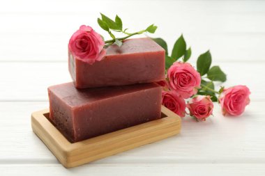 Sabun çubukları ve beyaz ahşap masada güzel güller, yakın plan.