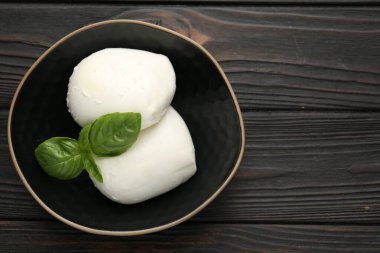 Ahşap masadaki fesleğen ve mozzarella peyniri parçaları, üst manzara. Metin için boşluk