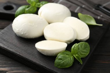 Nefis mozzarella peyniri ve fesleğen parçaları ahşap masada, yakın plan.