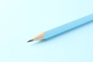 Açık mavi arkaplanda bir grafit kalem, yakın plan.