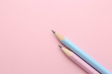 Pembe arka planda iki grafit kalem, düz. Metin için boşluk