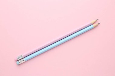 Pembe arka planda iki grafit kalem, düz.