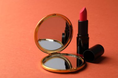 Mercan zemininde cep aynası ve ruj izi, yakın plan.