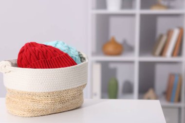 Hasır sepetteki farklı yün şapkalar beyaz masa içinde, mesaj için yer var.