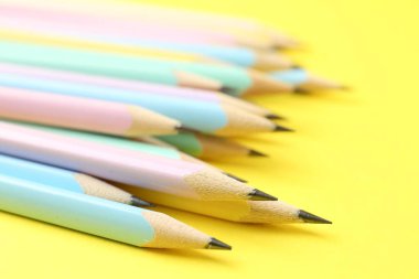 Sarı arkaplanda birçok grafit kalem, yakın plan