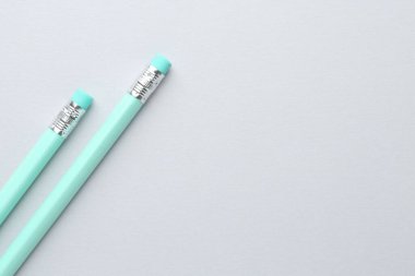 Açık gri arka planda silgisi olan iki grafit kalem, düz. Metin için boşluk