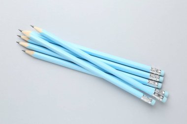 Açık gri arkaplanda silgileri olan bir sürü grafit kalem, düz konum