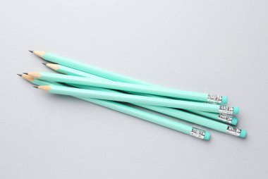 Açık gri arkaplanda silgileri olan bir sürü grafit kalem, düz konum