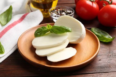 Lezzetli mozzarella, domates ve fesleğen ahşap masada, yakın plan.