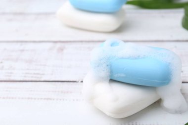 Beyaz ahşap masada köpüklü sabun çubukları, yakın plan. Metin için boşluk