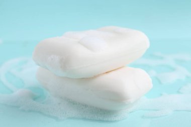 Açık mavi arka planda köpüklü sabun çubukları, yakın plan