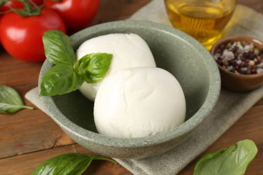 Lezzetli mozarella topları, domatesler ve fesleğenler ahşap masada, yakın plan.