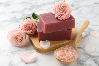 Sabun çubukları, deniz tuzu ve beyaz mermer masada güzel güller, yakın plan.