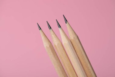 Many graphite pencils on pink background, closeup