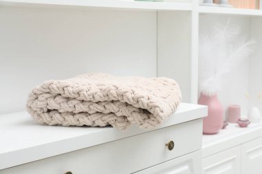 Beyaz çekmecelerin üzerindeki yün battaniye kapalı, yakın plan.