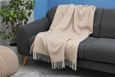 Oturma odasındaki kanepede bej yün battaniye.