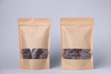 Açık gri arka planda kahve çekirdekli fermuar stand-up torbaları. Tasarım için model