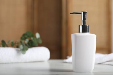 Şişedeki sıvı sabun, havlular ve okaliptüs dalı beyaz mermer masa içinde, metin için yer var.