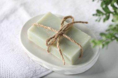 Sabun barı, havlu ve çiçek dekoru beyaz masada, yakın plan.