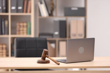 Hakimin tokmağı ve dizüstü bilgisayarı ofisteki ahşap masada.