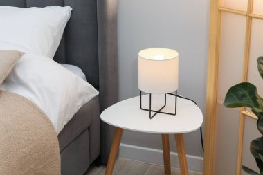 Yan masada yatağın yanında lamba var.