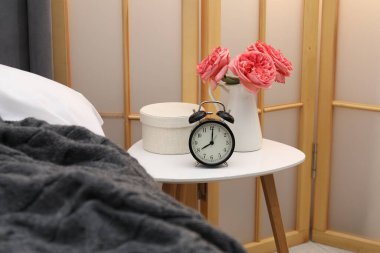 Çalar saati olan yan masa ve yatağın yanındaki dekor.